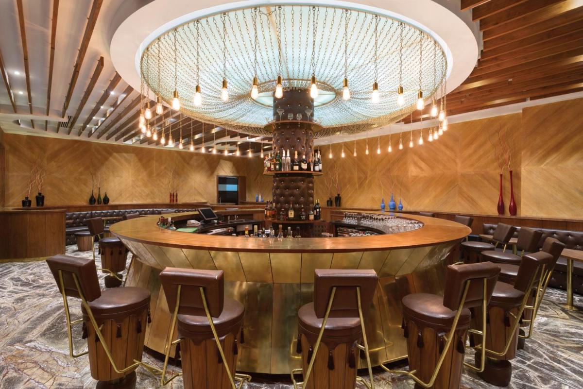 a bar in a restaurant with a large chandelier at Saura Hotel, Agra - A Club Mahindra Associate in Agra