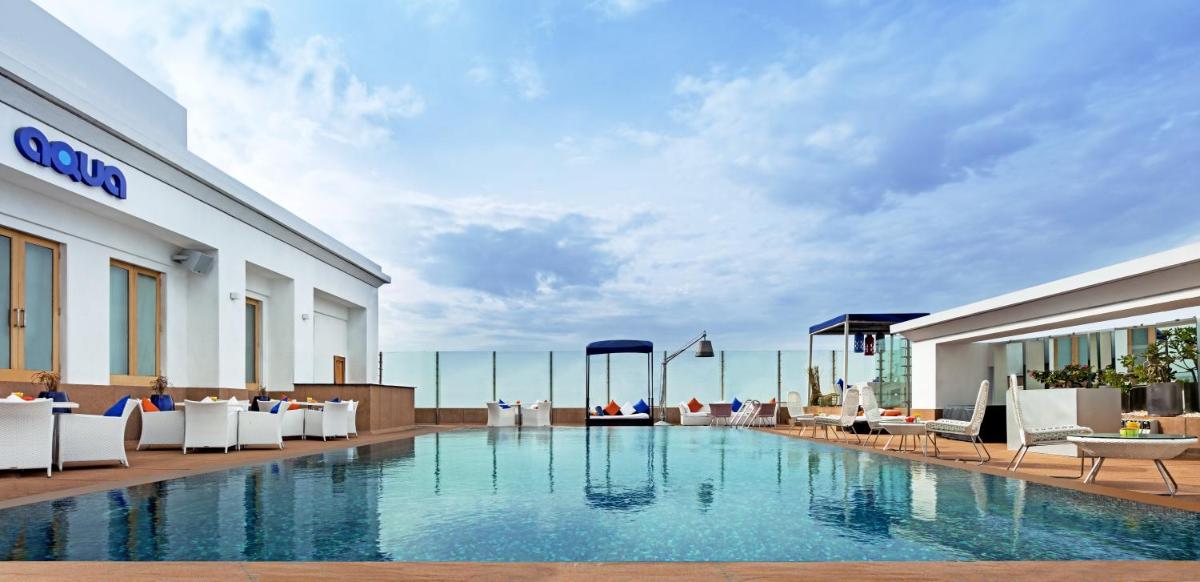 a pool in a hotel with chairs and tables at The Park Chennai in Chennai a pool in a hotel with chairs and tables at The Park Chennai in Chennai