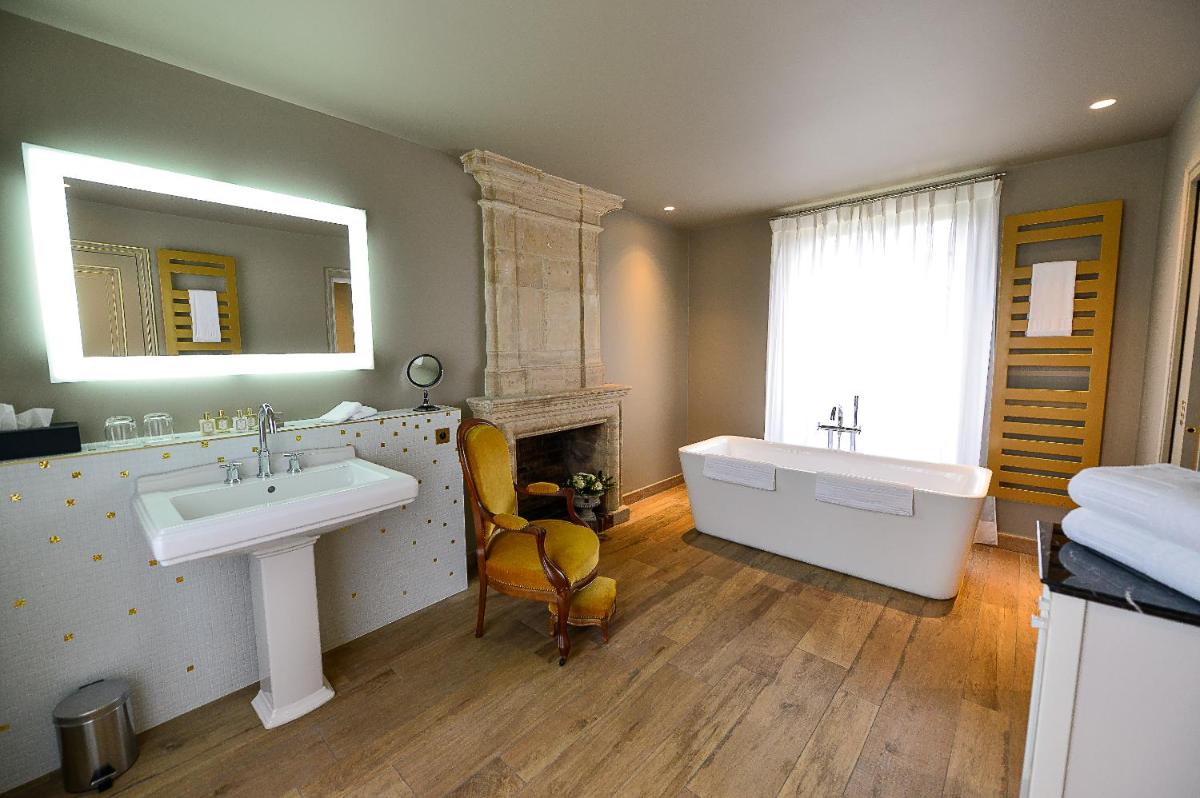 une salle de bain avec un lavabo et une baignoire et une cheminée dans l'établissement Chateau d'Audrieu, à Audrieu