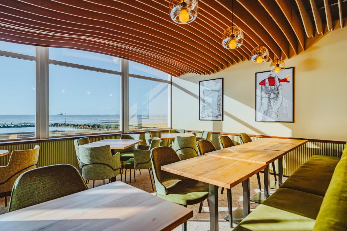 un restaurant avec des tables, des chaises et des fenêtres dans l'établissement Hotel Atlantic, à Wimereux