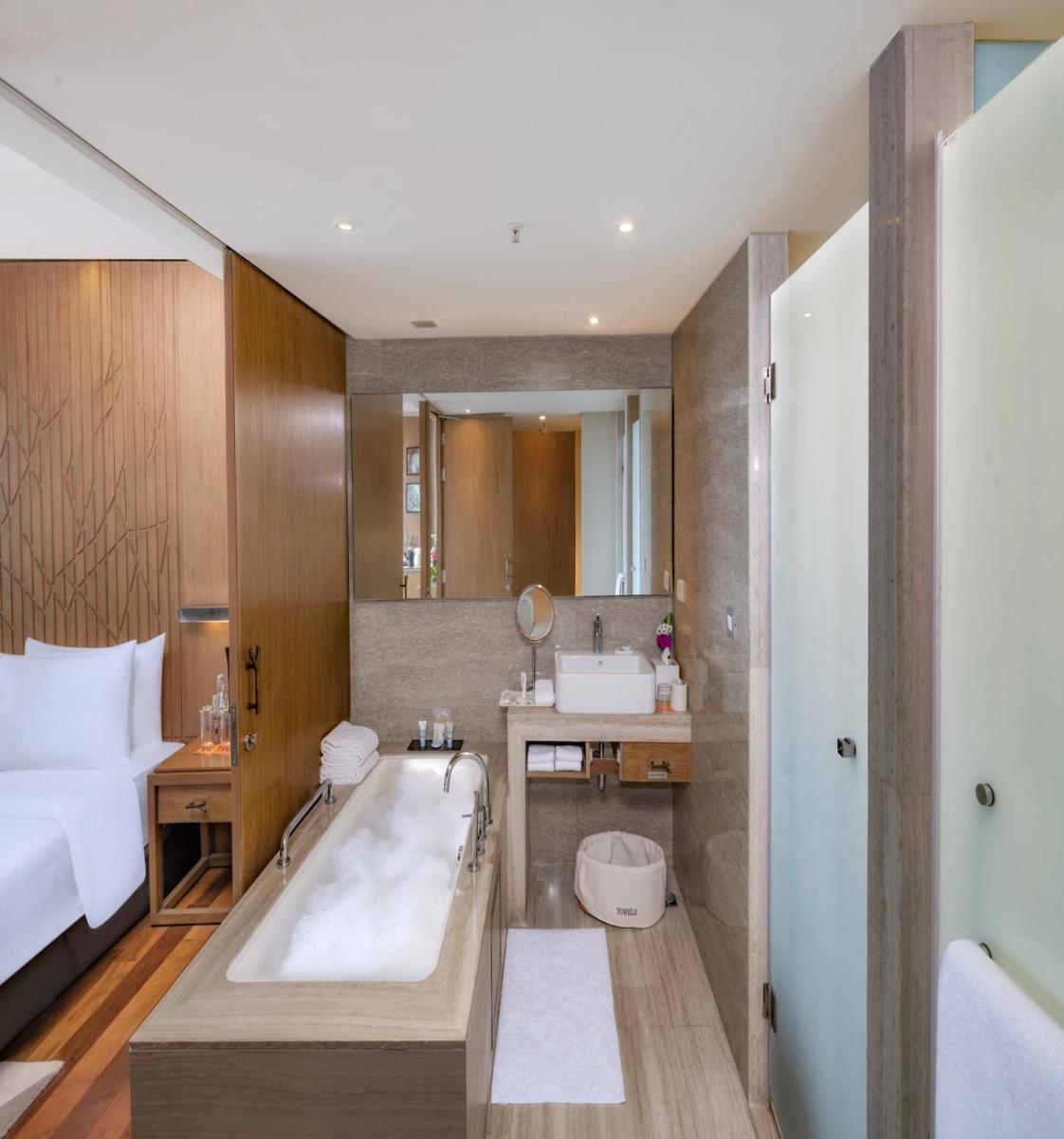 a bathroom with a bath tub and a bed at Welcomhotel by ITC Hotels, Richmond Road, Bengaluru in Bengaluru