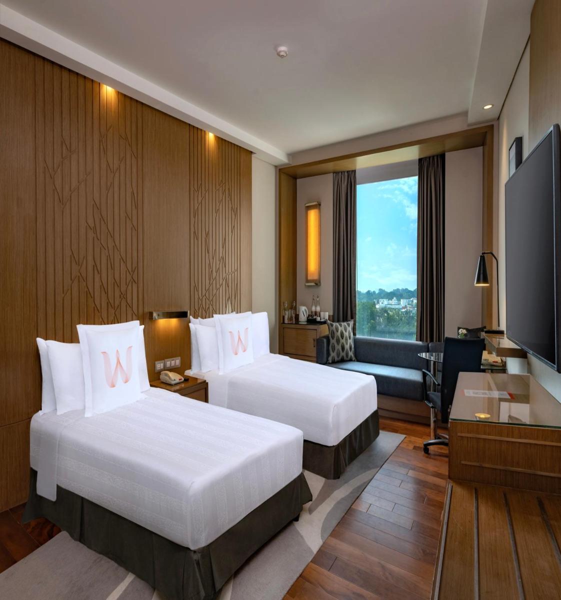 a hotel room with two beds and a flat screen tv at Welcomhotel by ITC Hotels, Richmond Road, Bengaluru in Bengaluru