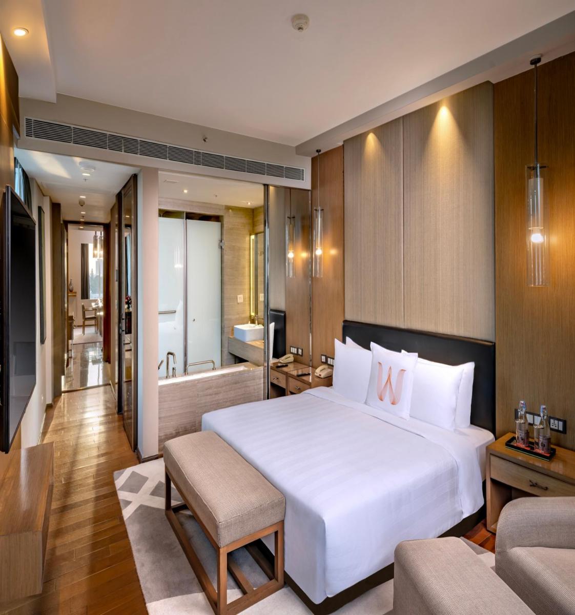 a bedroom with a large white bed and a bathroom at Welcomhotel by ITC Hotels, Richmond Road, Bengaluru in Bengaluru