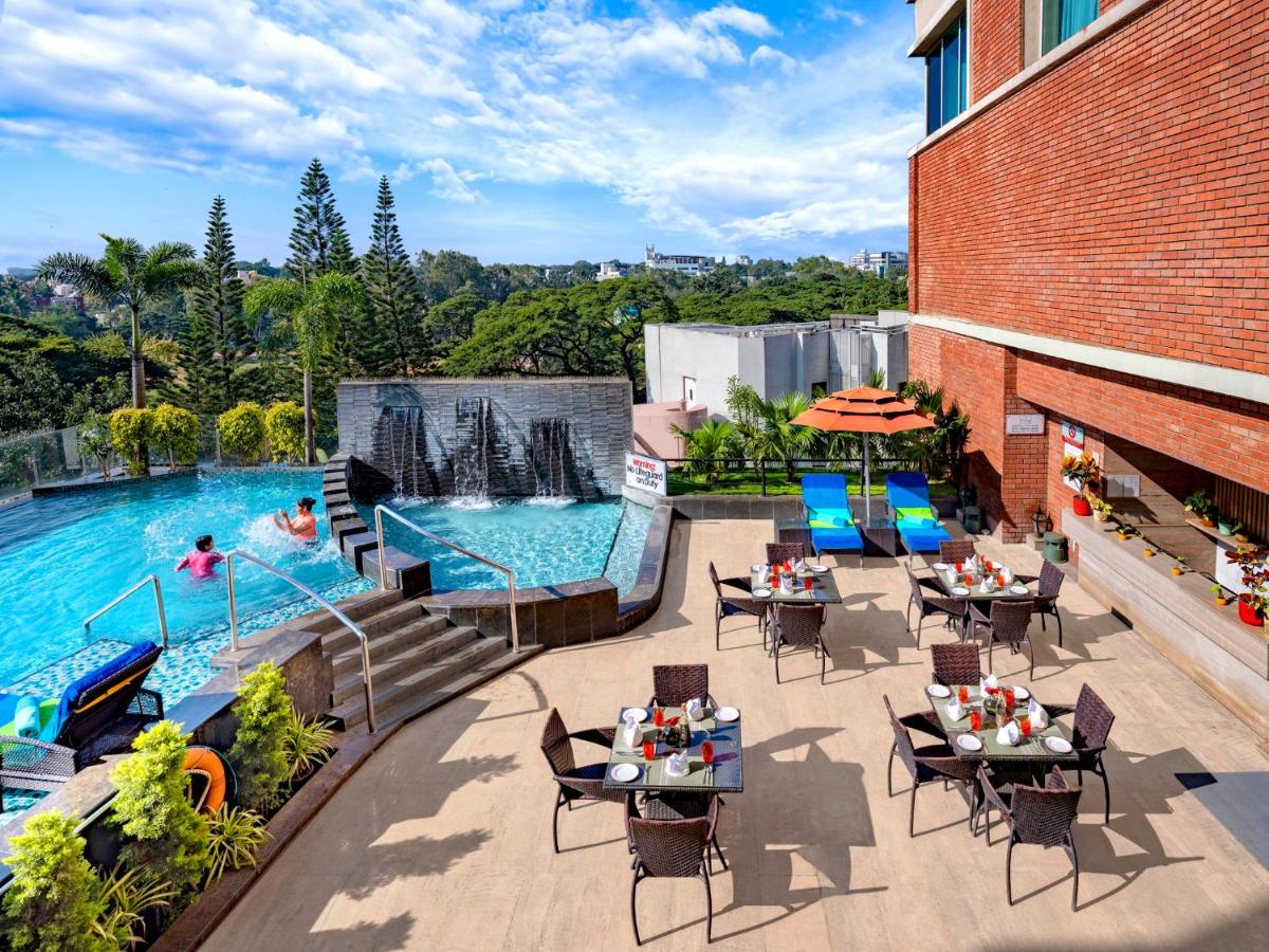 an outdoor patio with tables and chairs and a swimming pool at Welcomhotel by ITC Hotels, Richmond Road, Bengaluru in Bengaluru