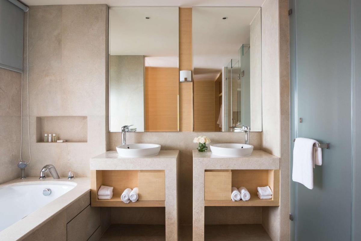a bathroom with two sinks and a tub and a mirror at Hyatt Regency Lucknow Gomti Nagar in Lucknow