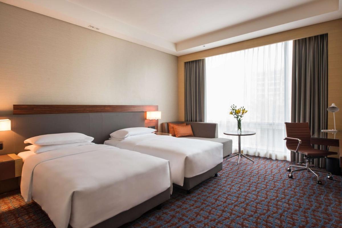 a hotel room with two beds and a desk at Hyatt Regency Lucknow Gomti Nagar in Lucknow