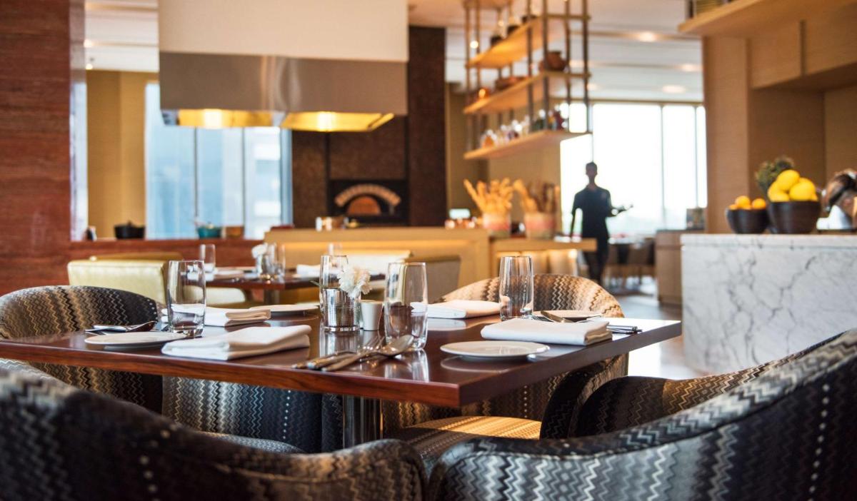 a restaurant with a wooden table and chairs at Hyatt Regency Lucknow Gomti Nagar in Lucknow