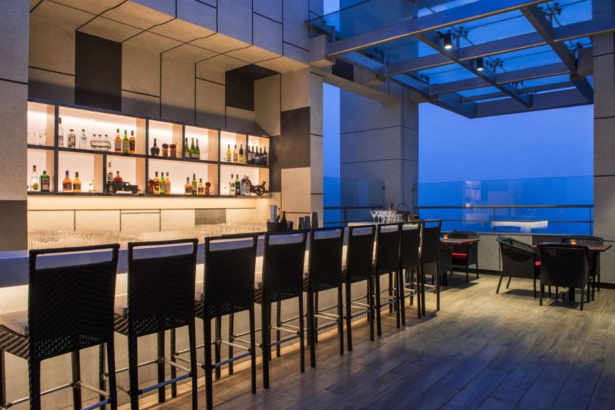 a restaurant with a bar with chairs and tables at Hyatt Regency Lucknow Gomti Nagar in Lucknow