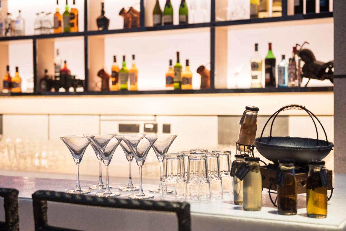 a bar with wine glasses on a counter with bottles at Hyatt Regency Lucknow Gomti Nagar in Lucknow