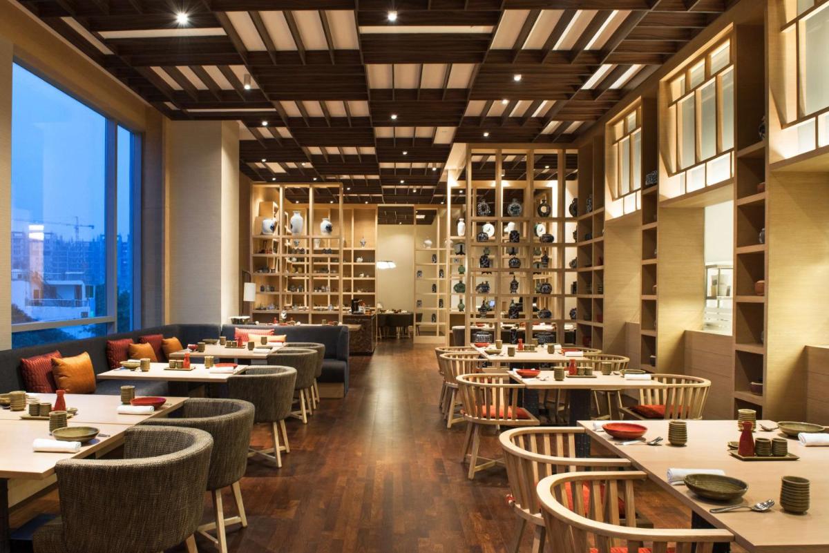 a restaurant with tables and chairs and a large window at Hyatt Regency Lucknow Gomti Nagar in Lucknow