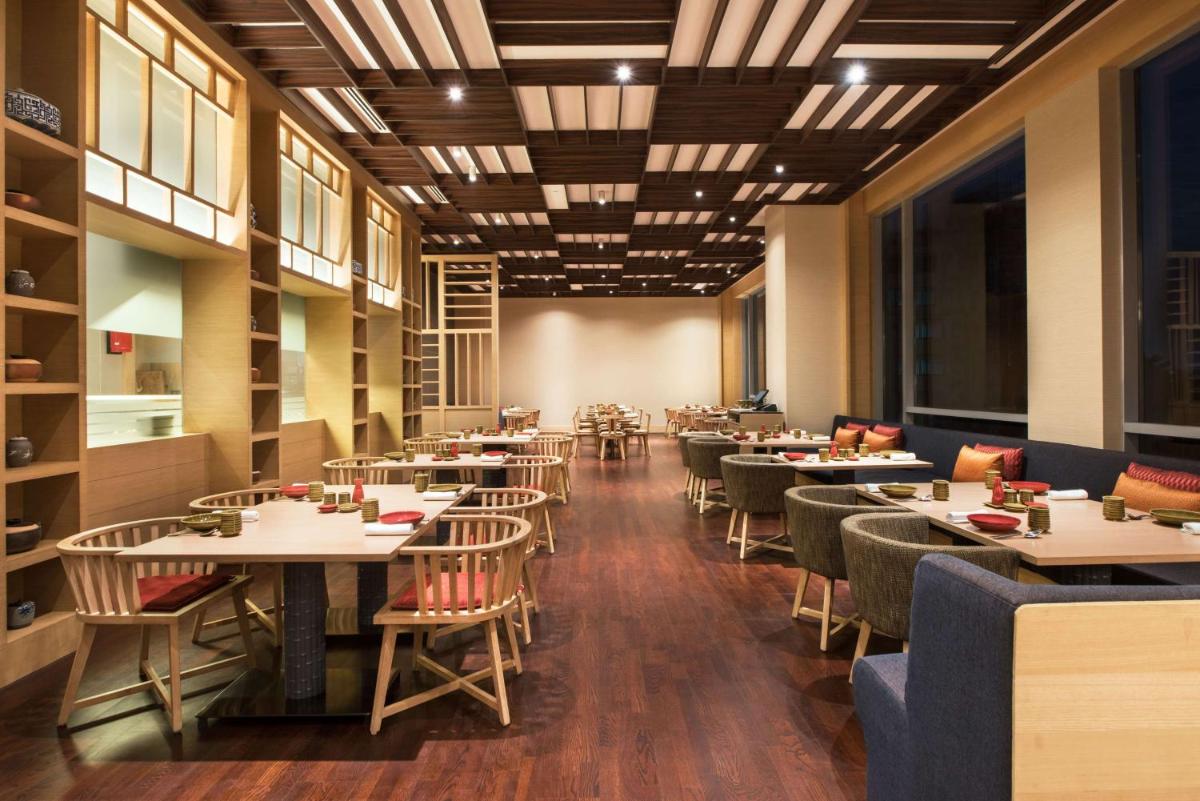 a dining room with tables and chairs and windows at Hyatt Regency Lucknow Gomti Nagar in Lucknow