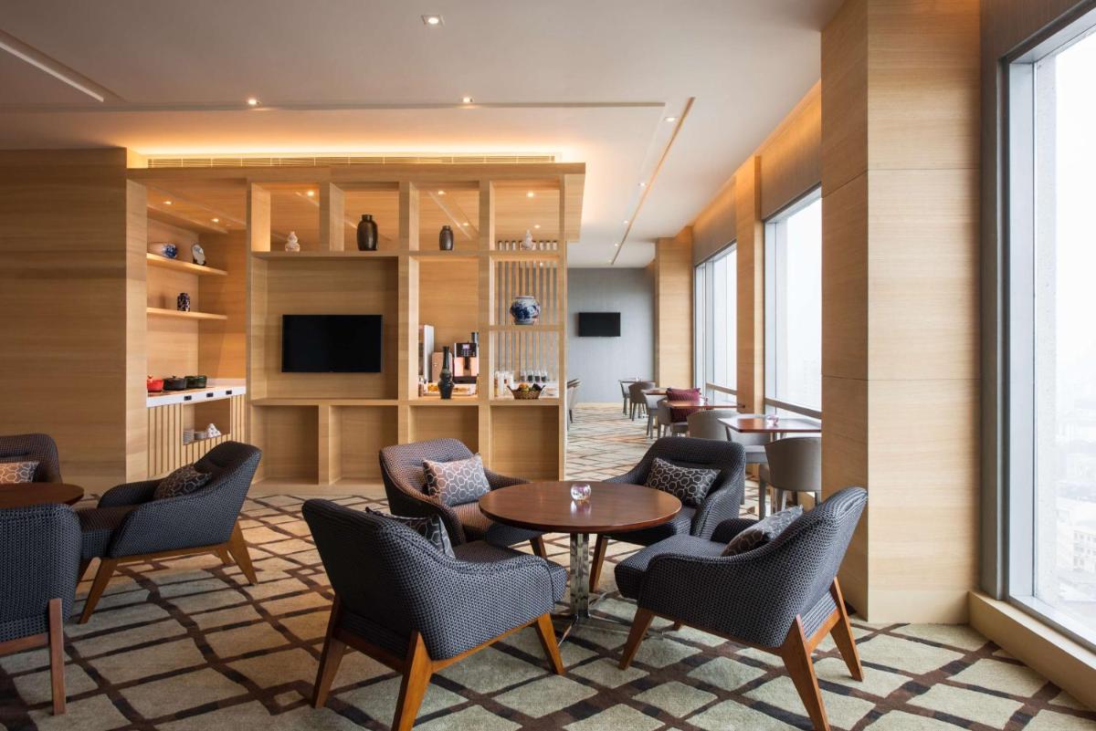 a waiting room with chairs and a table and a tv at Hyatt Regency Lucknow Gomti Nagar in Lucknow