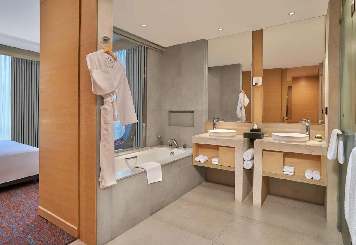 a bathroom with two sinks and a bath tub and a mirror at Hyatt Regency Lucknow Gomti Nagar in Lucknow