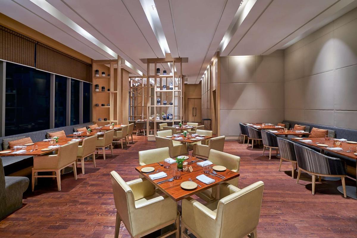a restaurant with tables and chairs in a room at Hyatt Regency Lucknow Gomti Nagar in Lucknow