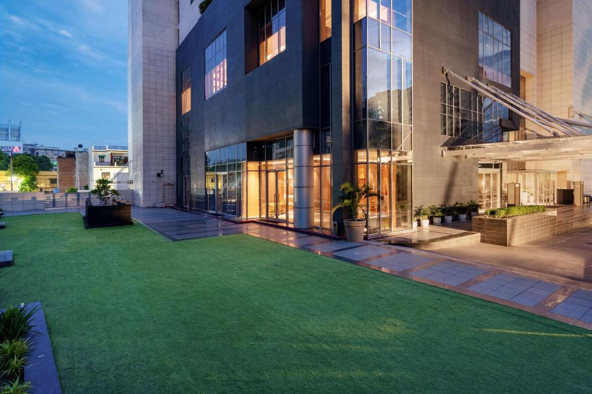 a large building with a green lawn in front of it at Hyatt Regency Lucknow Gomti Nagar in Lucknow