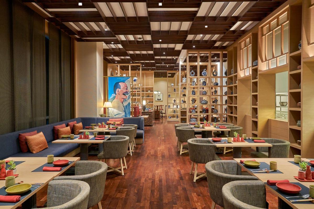 a restaurant with tables and chairs and a painting on the wall at Hyatt Regency Lucknow Gomti Nagar in Lucknow