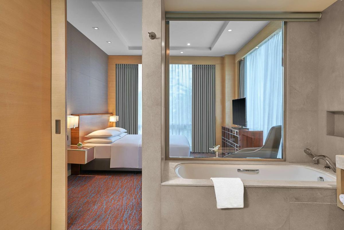 a bathroom with a tub and a bedroom with a bed at Hyatt Regency Lucknow Gomti Nagar in Lucknow