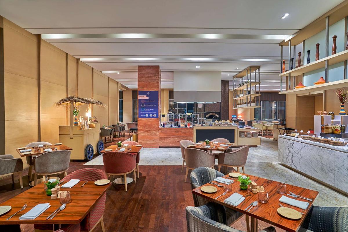 a restaurant with wooden tables and chairs and a counter at Hyatt Regency Lucknow Gomti Nagar in Lucknow