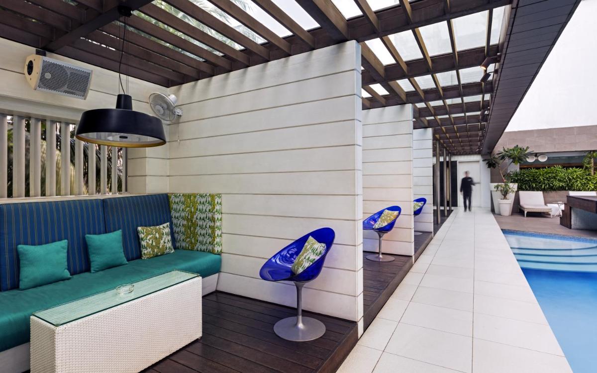 a pool room with a couch and chairs next to a pool at The Park Kolkata in Kolkata