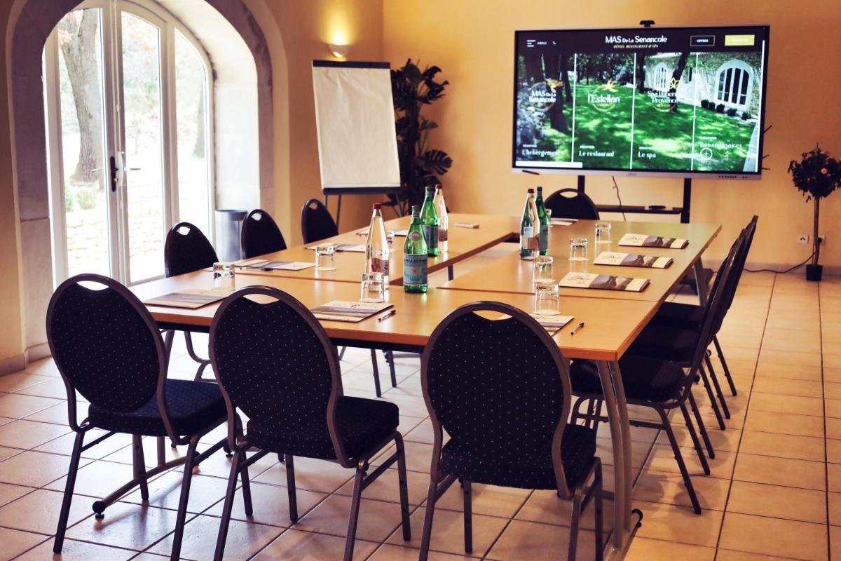 une salle de conférence avec une longue table avec des chaises et une télévision dans l'établissement Mas De La Senancole & Spa, à Gordes