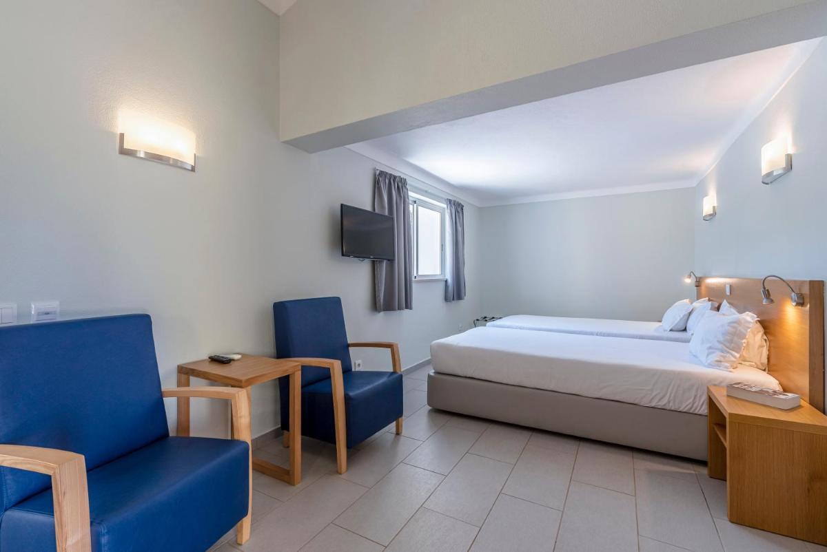 um quarto com uma cama e duas cadeiras azuis em Browns Sports Resort em Vilamoura mais 60 fotografias