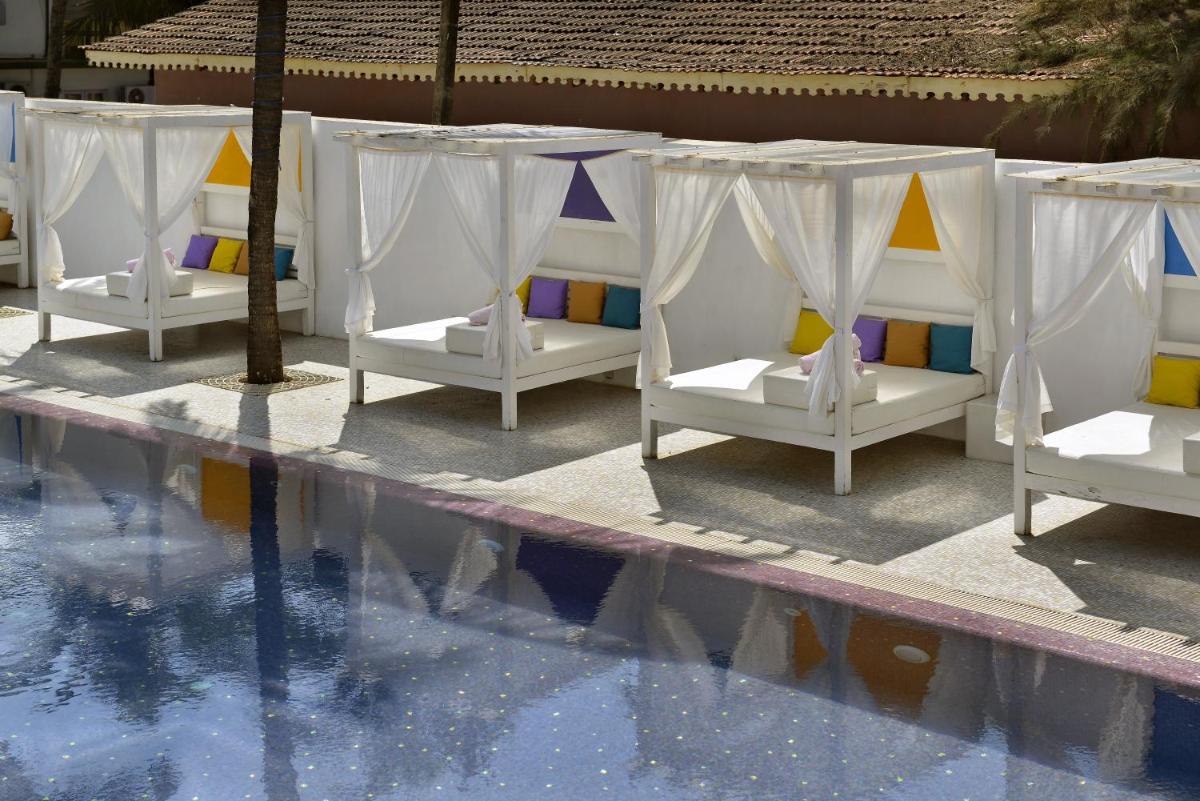 a group of white beds next to a swimming pool at The Park Calangute Goa in Calangute a group of white beds next to a swimming pool at The Park Calangute Goa in Calangute