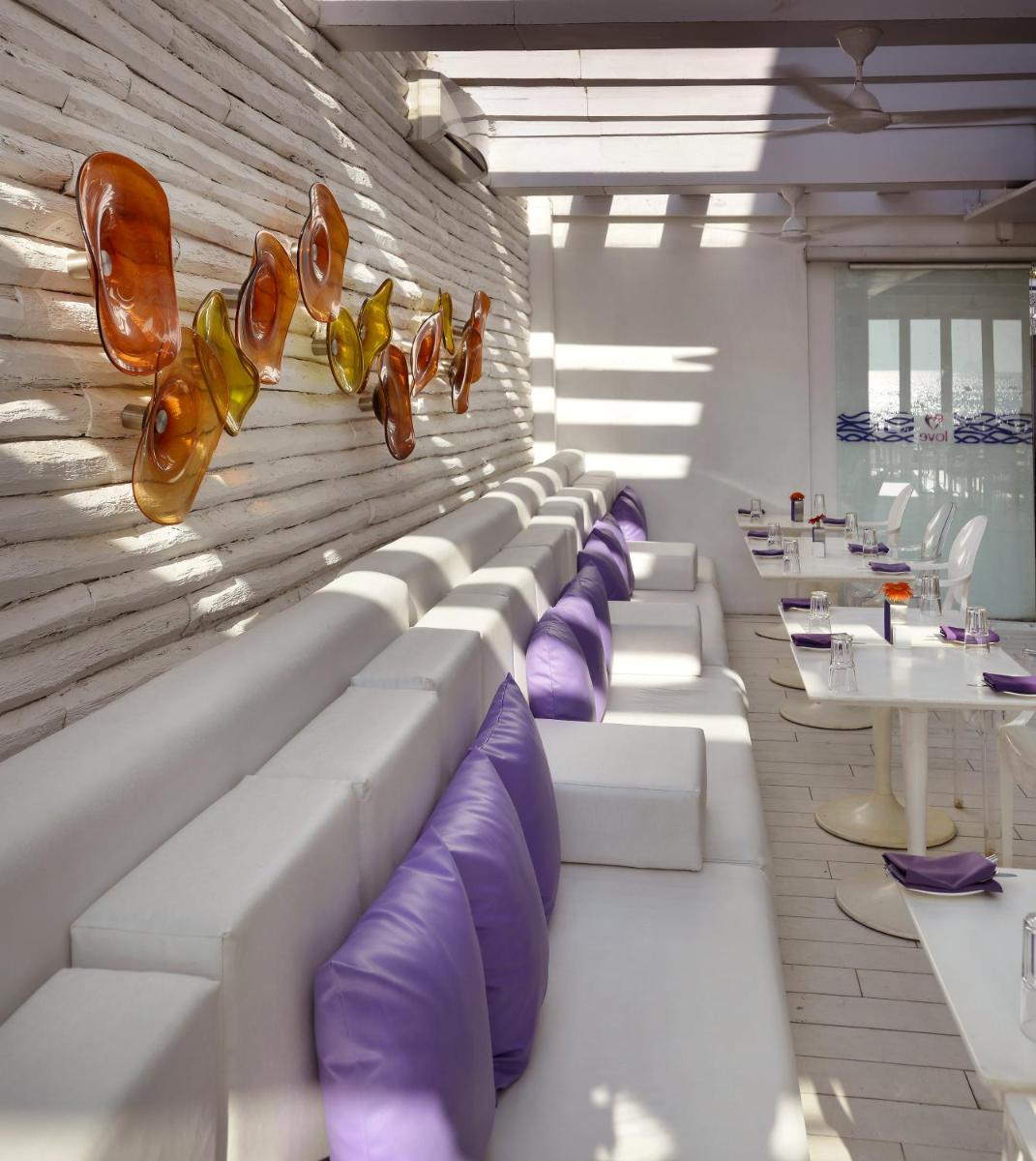 a row of couches in a room with purple cushions at The Park Calangute Goa in Calangute a row of couches in a room with purple cushions at The Park Calangute Goa in Calangute