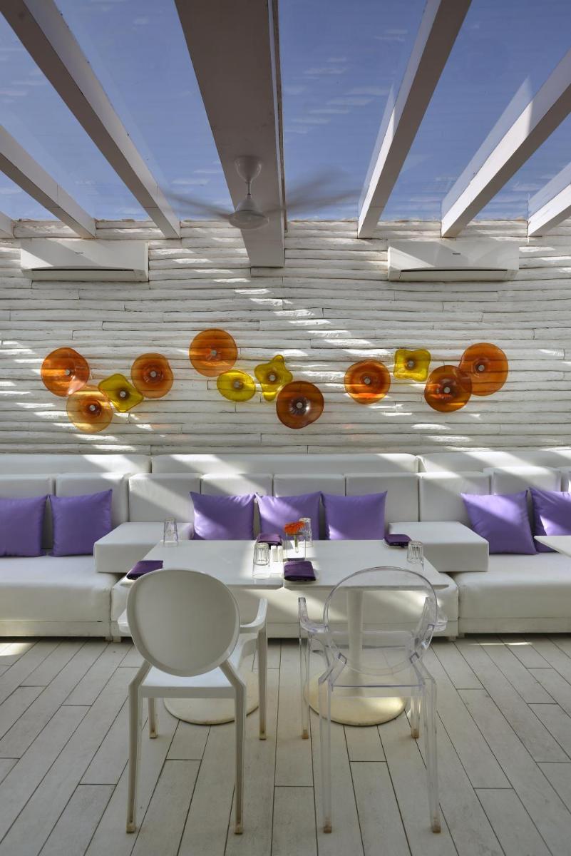 a dining room with a white table and purple pillows at The Park Calangute Goa in Calangute a dining room with a white table and purple pillows at The Park Calangute Goa in Calangute