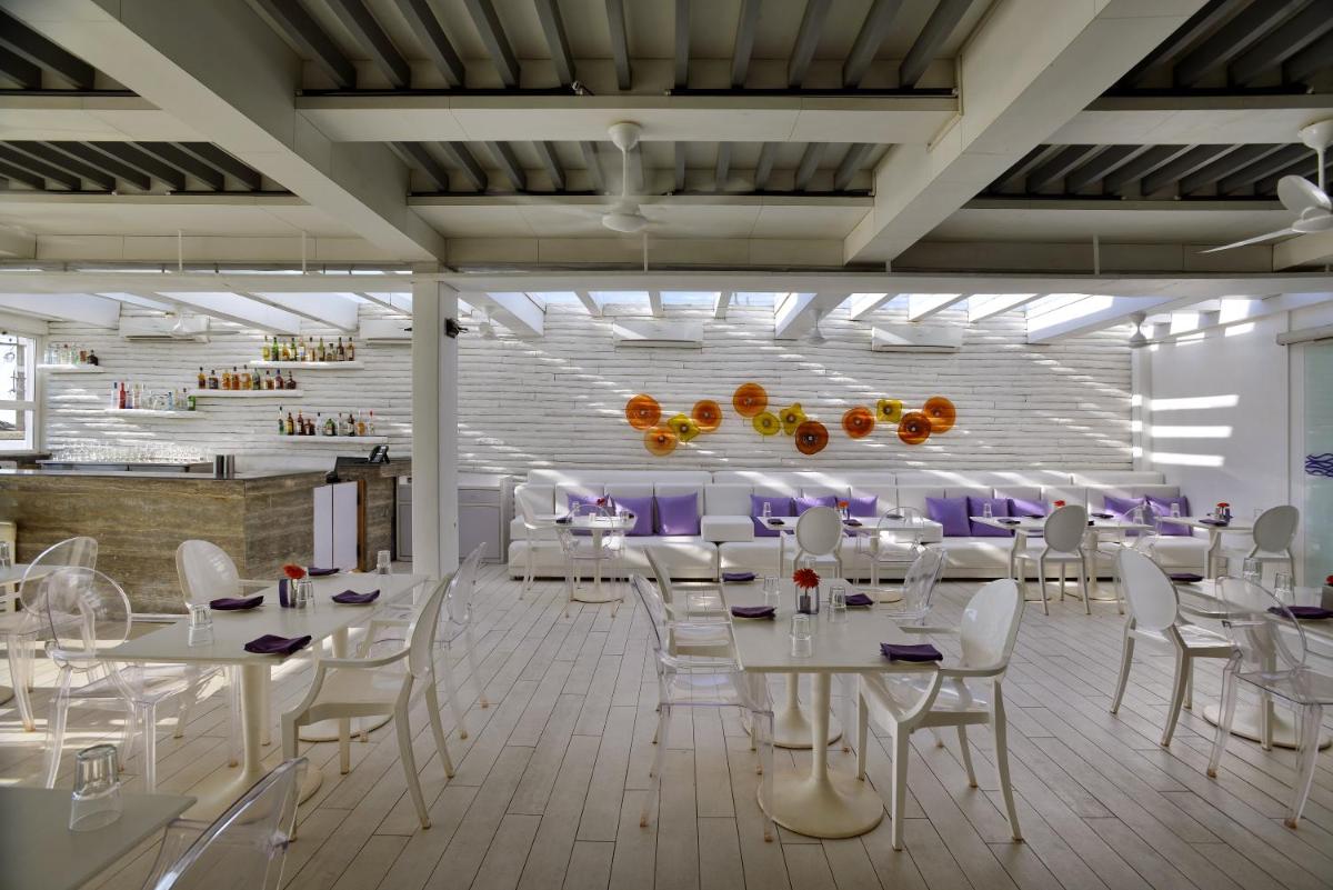 a dining room with white tables and white chairs at The Park Calangute Goa in Calangute a dining room with white tables and white chairs at The Park Calangute Goa in Calangute