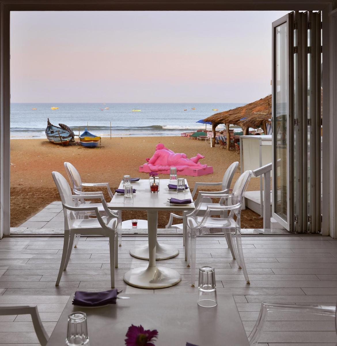 a table and chairs with a view of the beach at The Park Calangute Goa in Calangute a table and chairs with a view of the beach at The Park Calangute Goa in Calangute