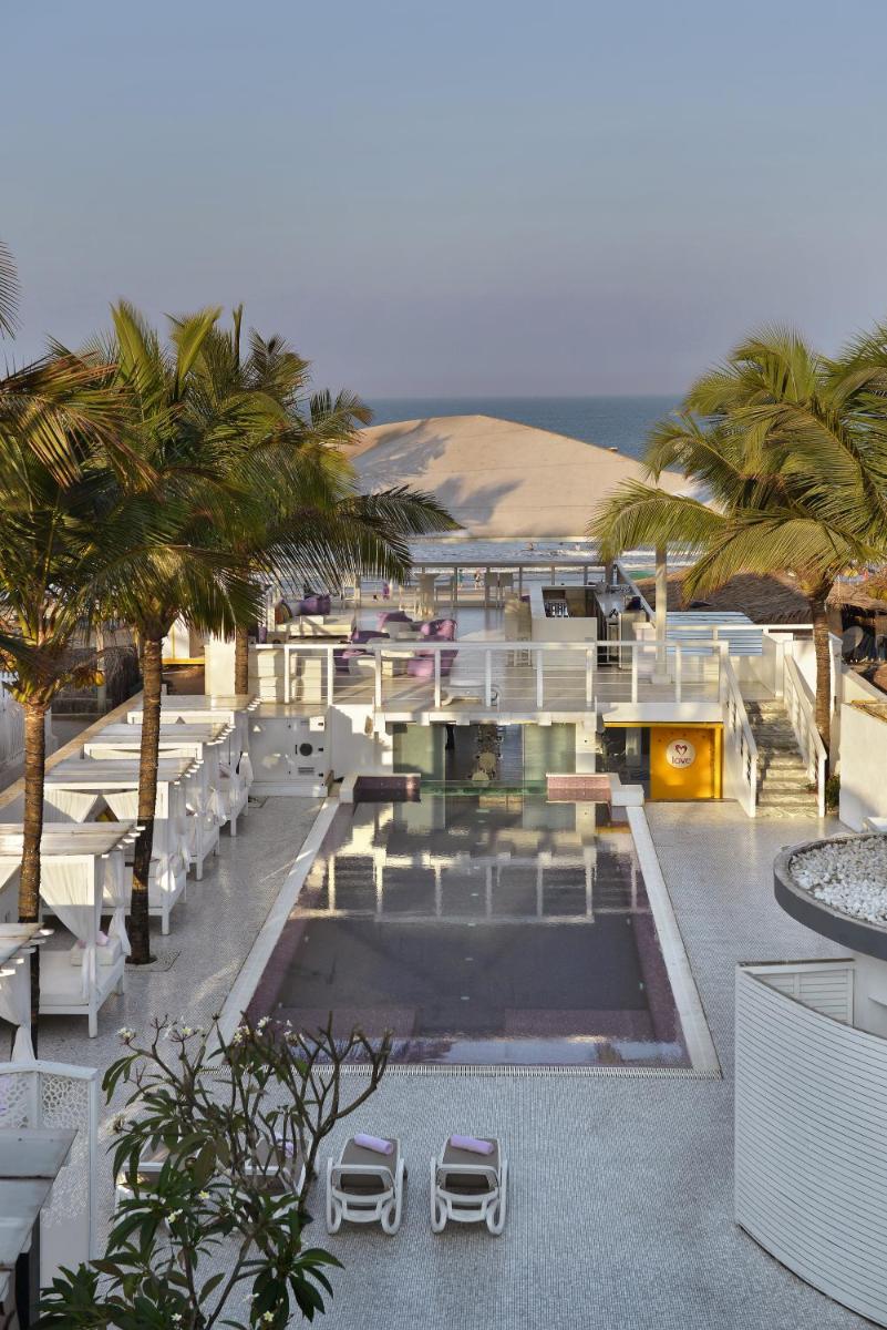 a resort with a pool and chairs and palm trees at The Park Calangute Goa in Calangute a resort with a pool and chairs and palm trees at The Park Calangute Goa in Calangute