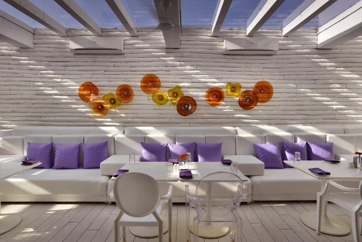 a dining room with white furniture and purple pillows at The Park Calangute Goa in Calangute a dining room with white furniture and purple pillows at The Park Calangute Goa in Calangute