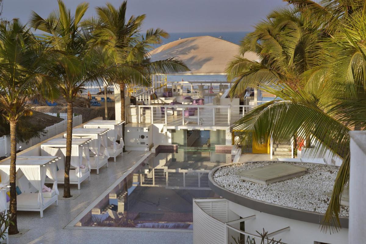 a view of a resort with white chairs and palm trees at The Park Calangute Goa in Calangute a view of a resort with white chairs and palm trees at The Park Calangute Goa in Calangute