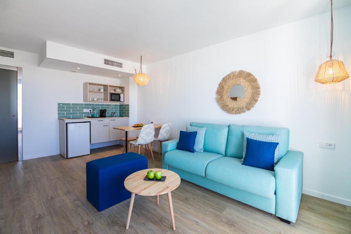 Una sala de estar con un sofá azul y una mesa. en MarSenses Rosa del Mar Hotel & Spa, en Palmanova