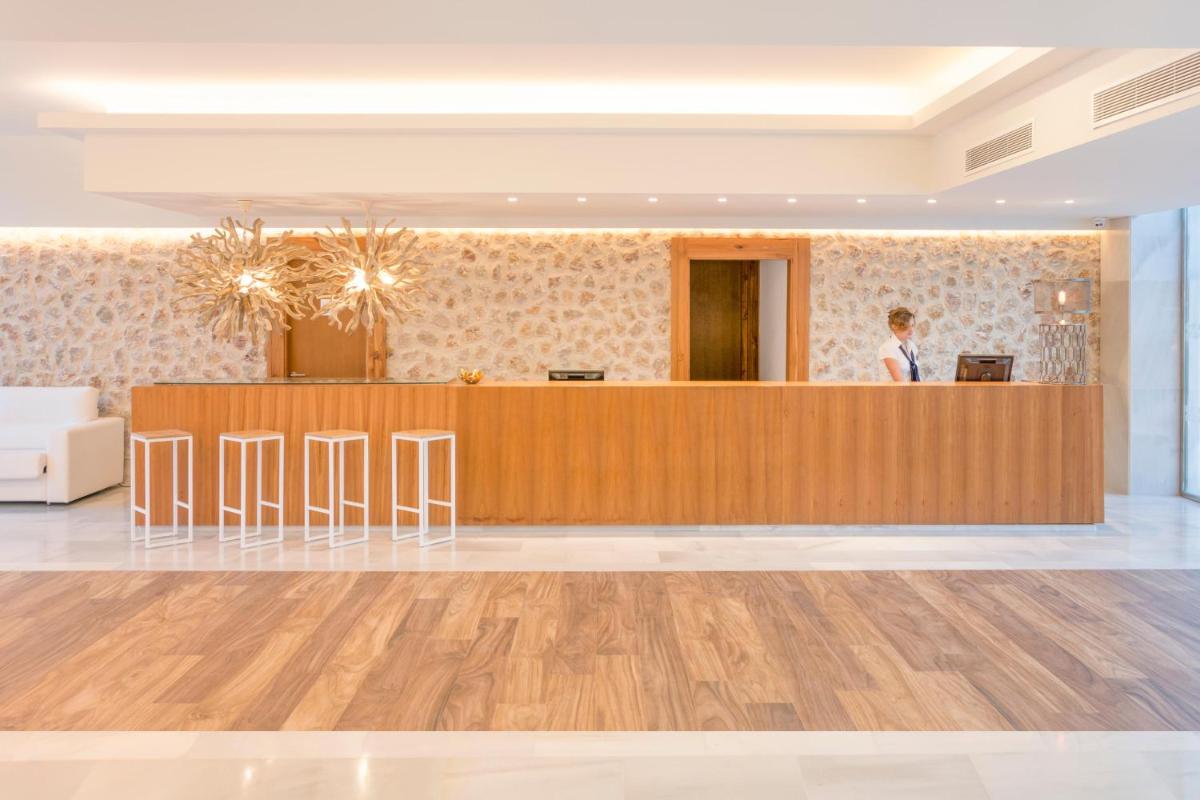 Una mujer parada en un mostrador de recepción en un vestíbulo. en MarSenses Puerto Pollensa Hotel & Spa Adults Only, en Puerto Pollensa