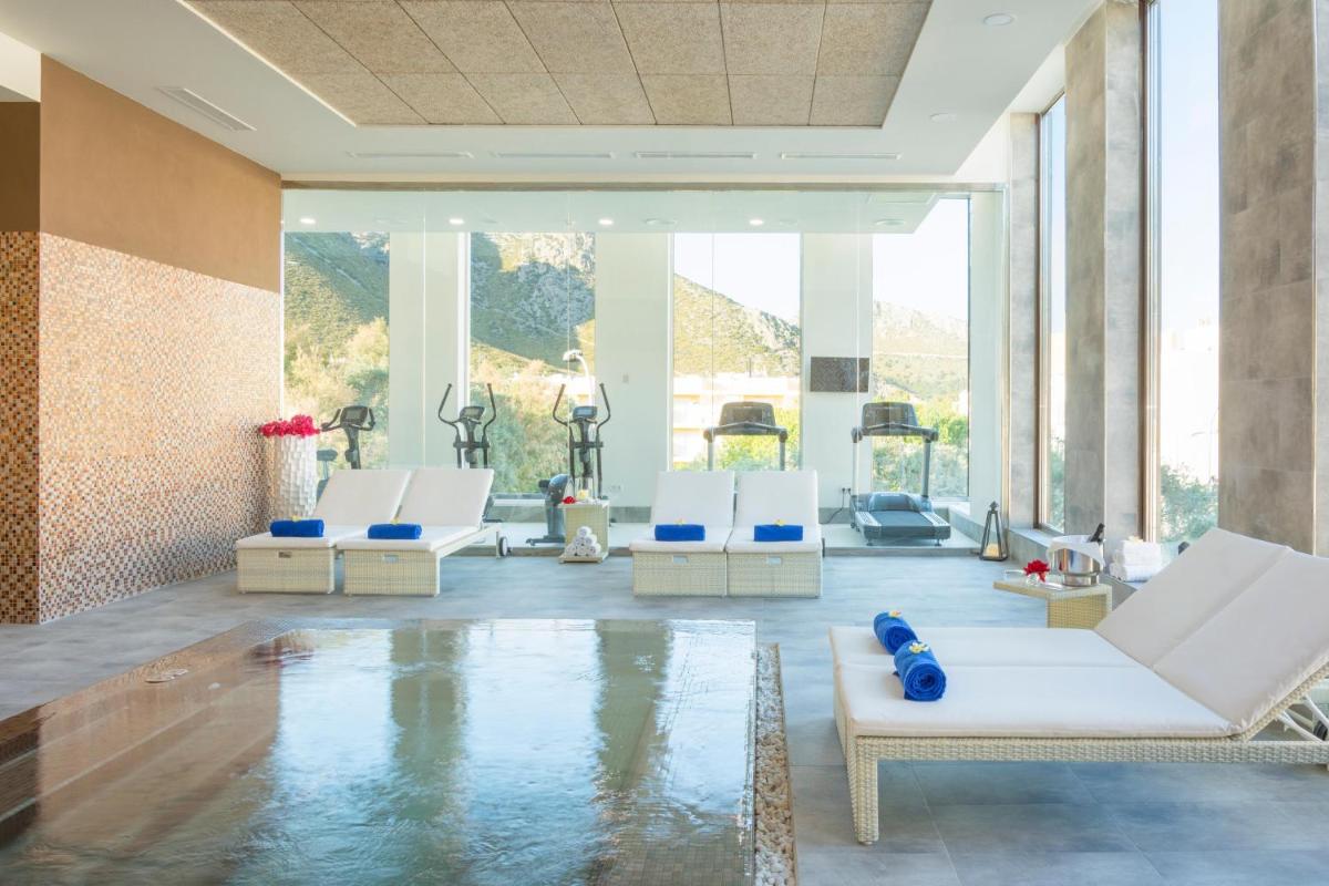 Una habitación con piscina con sillas blancas y agua. en MarSenses Puerto Pollensa Hotel & Spa Adults Only, en Puerto Pollensa
