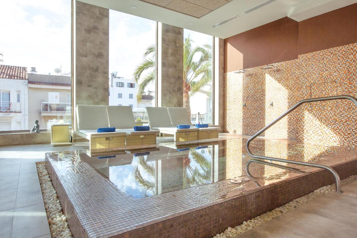 Un vestíbulo con piscina, mesas y ventanas. en MarSenses Puerto Pollensa Hotel & Spa Adults Only, en Puerto Pollensa