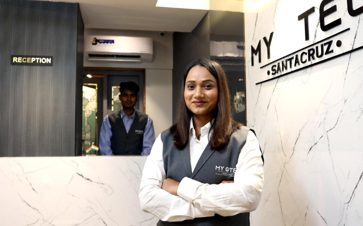 a woman standing in front of a wall with her arms crossed at MyOtel - Santacruz in Mumbai