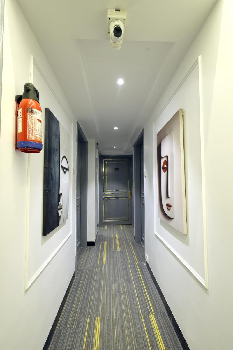 a hallway with a door and paintings on the walls at MyOtel - Santacruz in Mumbai