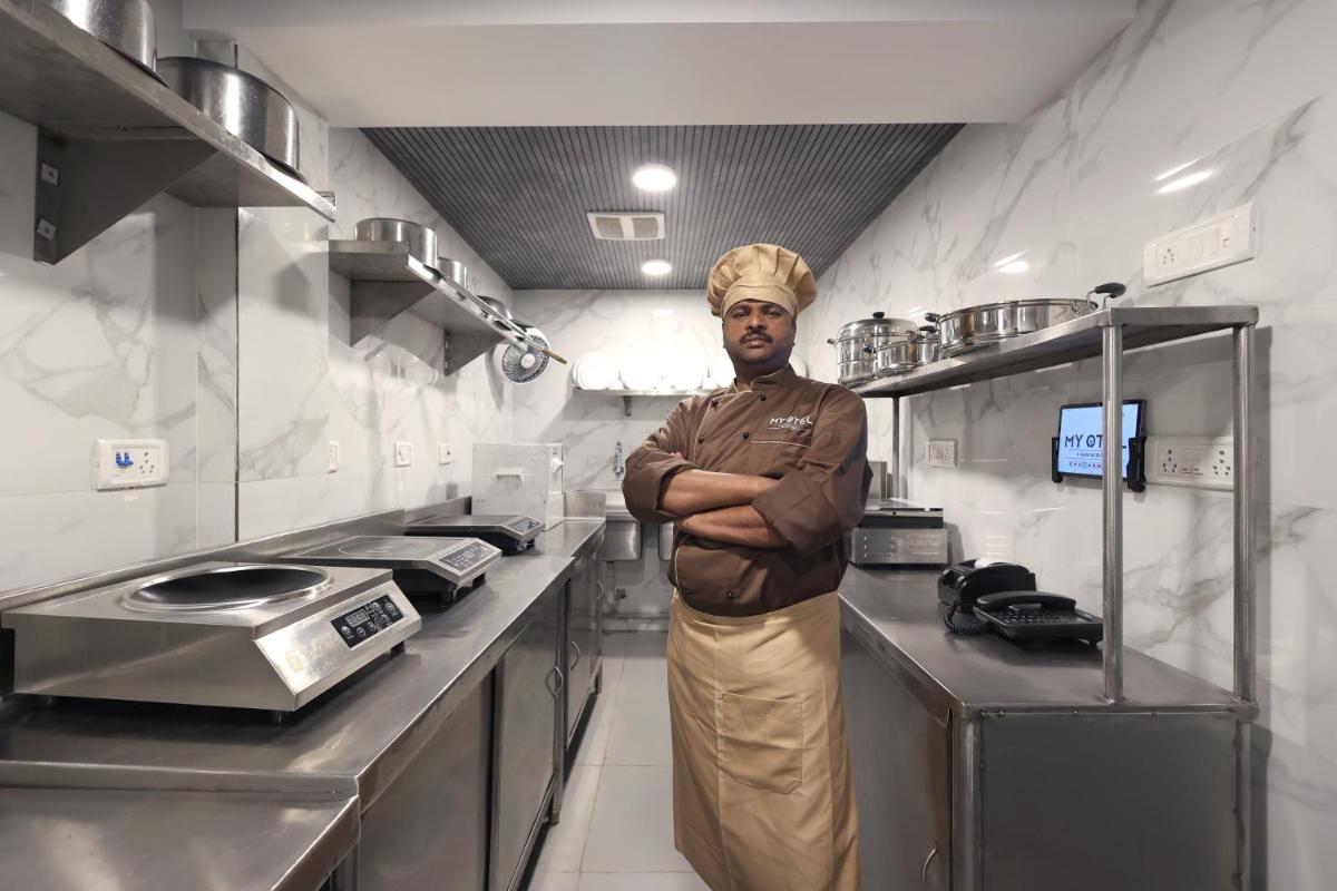 a man standing in a kitchen with his arms crossed at MyOtel - Santacruz in Mumbai