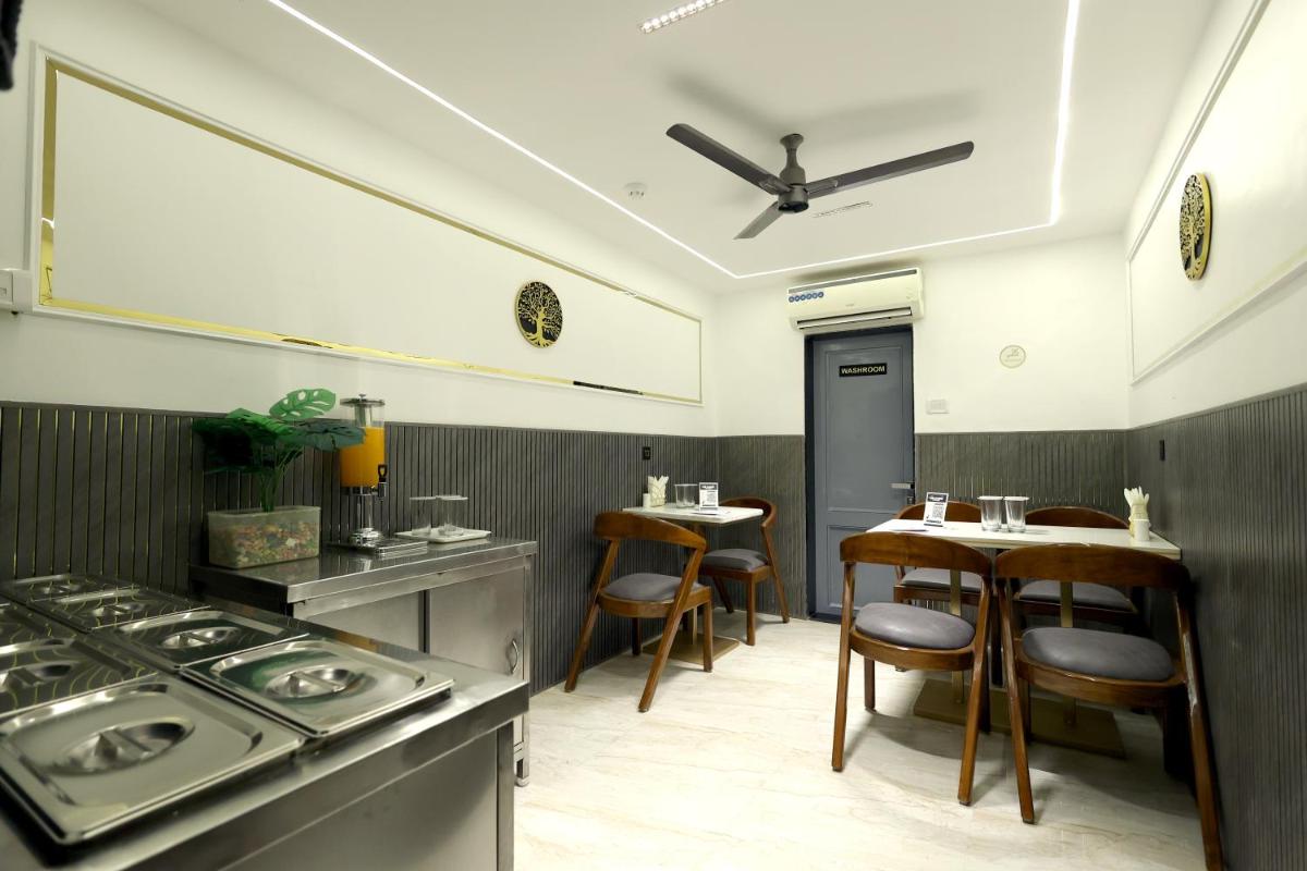 a kitchen with a stove and a table and chairs at MyOtel - Santacruz in Mumbai a kitchen with a stove and a table and chairs at MyOtel - Santacruz in Mumbai