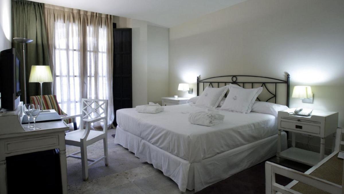 Un dormitorio con una cama, un escritorio y una silla. en Hotel Palacio de Mengibar, en Mengíbar