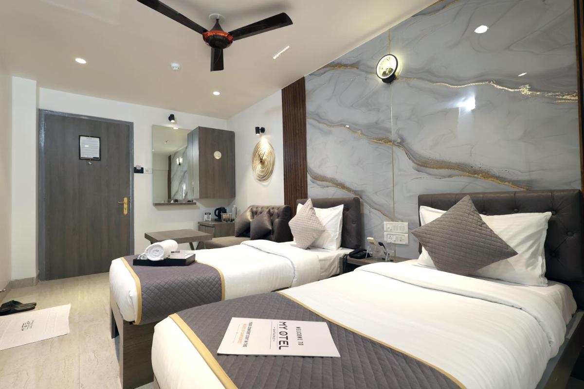a hotel room with two beds and a stone wall at MyOtel - Santacruz in Mumbai a hotel room with two beds and a stone wall at MyOtel - Santacruz in Mumbai