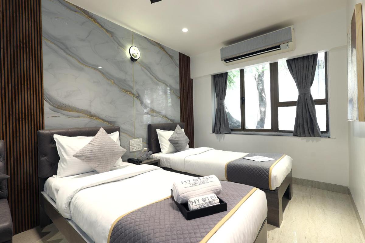 a hotel room with two beds and a window at MyOtel - Santacruz in Mumbai