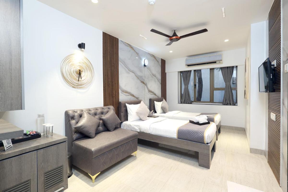 a bedroom with a bed and a chair and a television at MyOtel - Santacruz in Mumbai