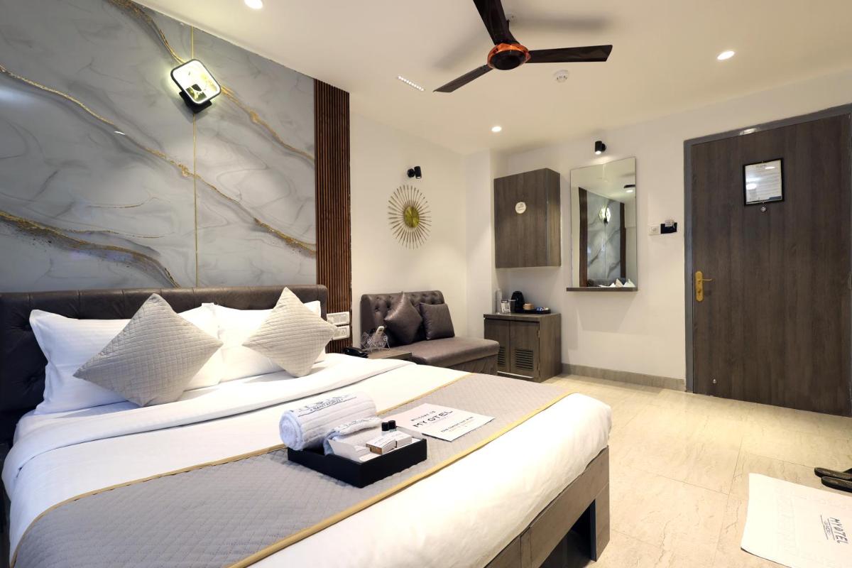 a bedroom with a large bed with a ceiling fan at MyOtel - Santacruz in Mumbai