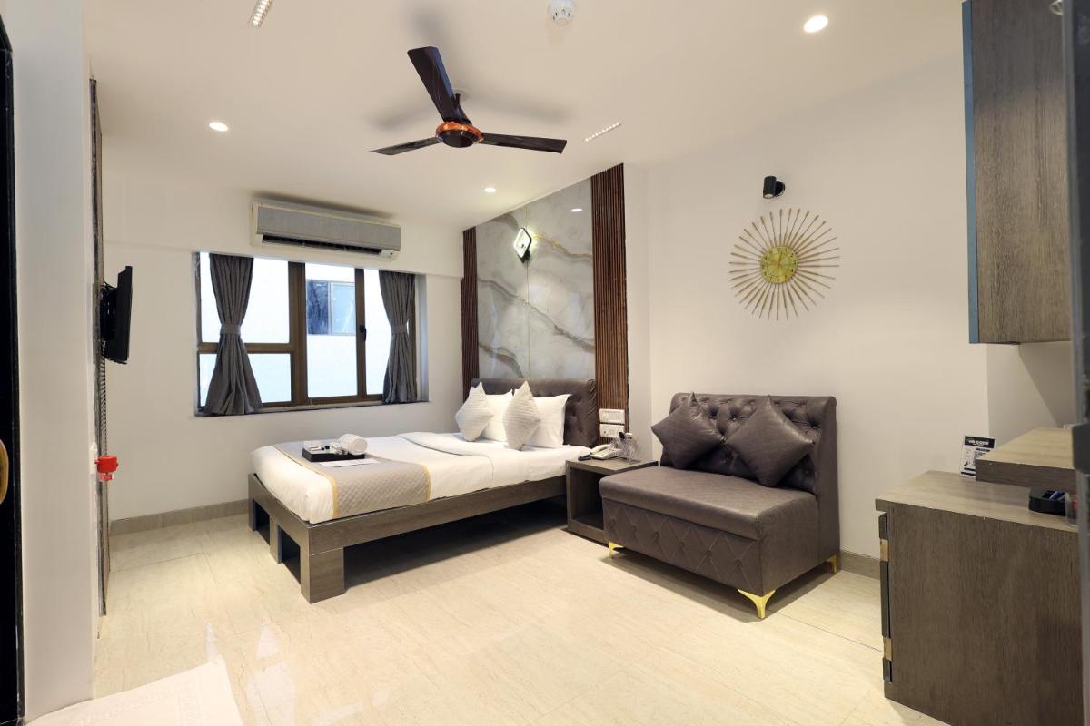 a bedroom with a bed and a couch and a chair at MyOtel - Santacruz in Mumbai