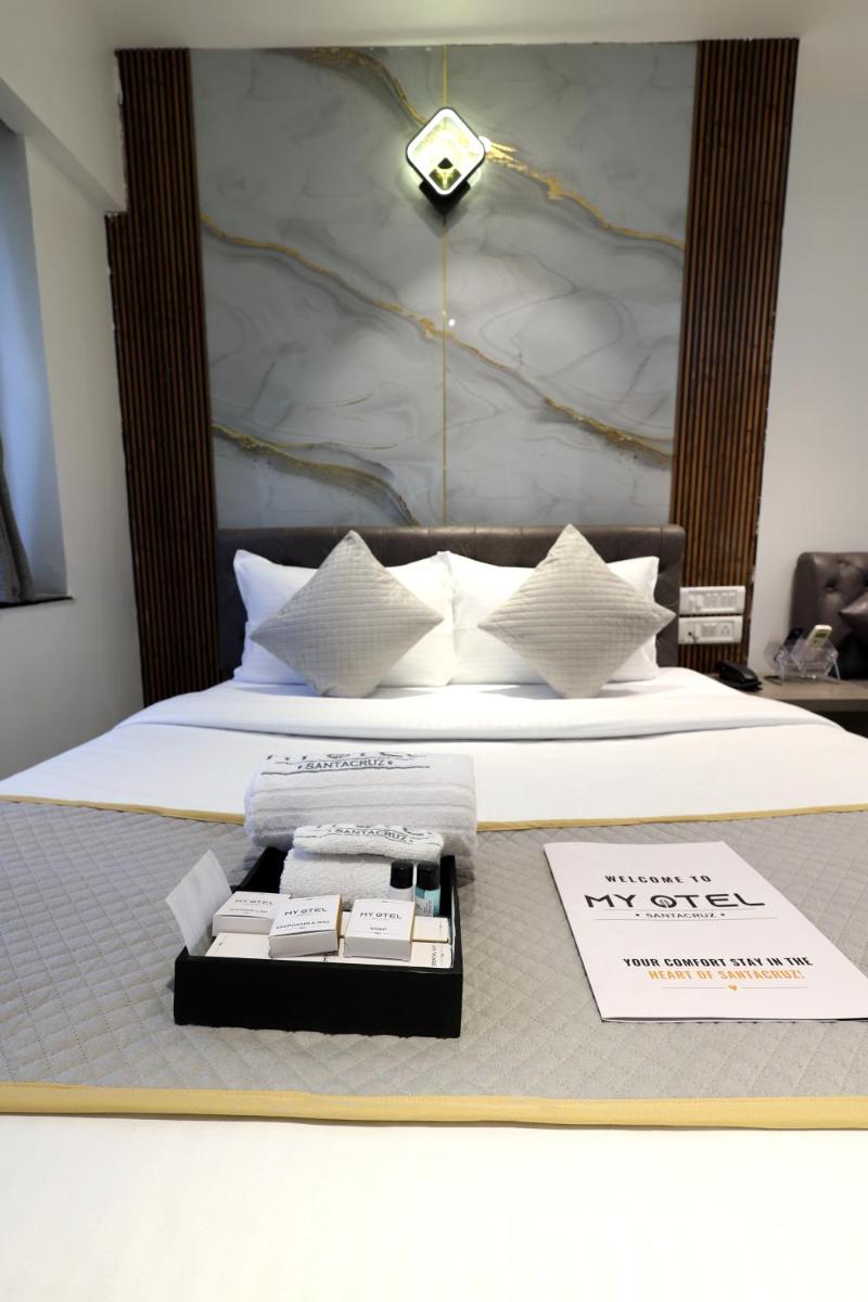 a hotel bed with a tray of books on it at MyOtel - Santacruz in Mumbai