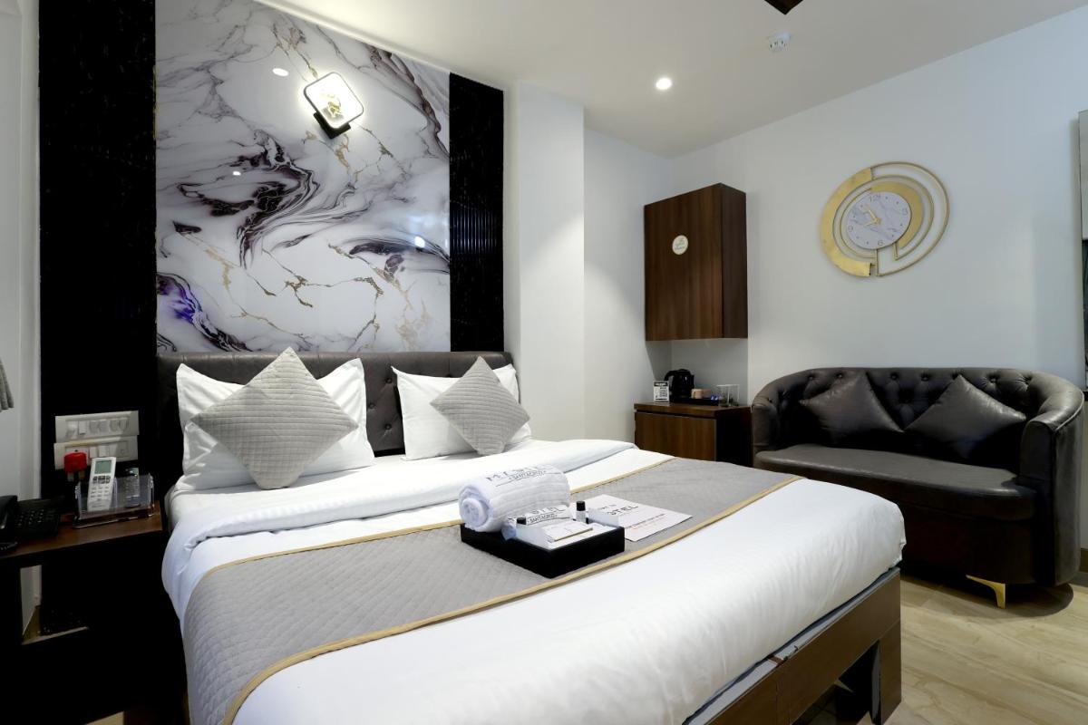 a bedroom with a large bed and a chair at MyOtel - Santacruz in Mumbai