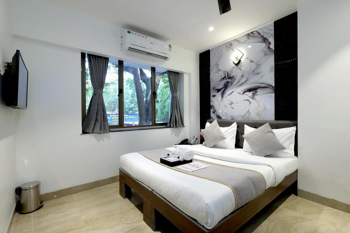 a bedroom with a bed with white walls and windows at MyOtel - Santacruz in Mumbai